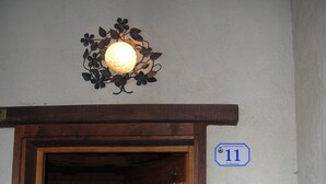 Eine Holztür mit einem Metallgitter, einer Wandleuchte und einem Blumentopf.