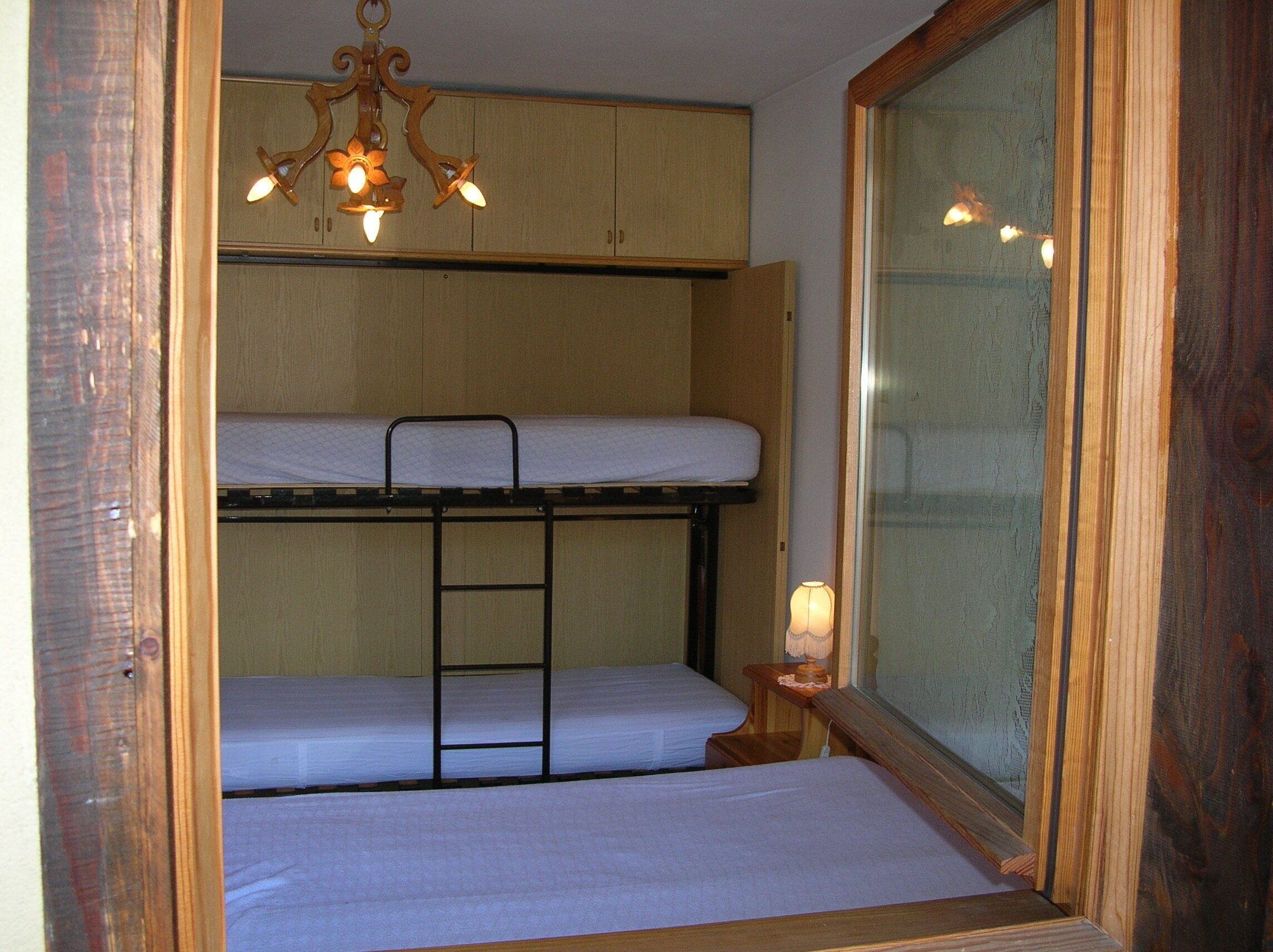 Habitación con literas, techo de madera y candelabro.