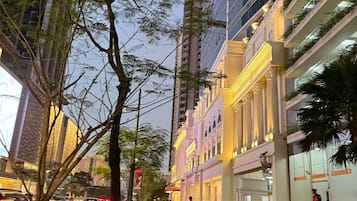 A street view with a building featuring a yellow facade and classical architecture, including columns and a balcony.