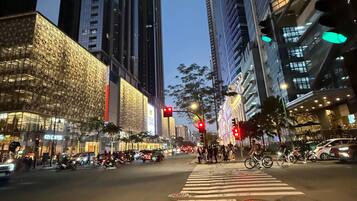 A city street at night with tall buildings, a crosswalk, and traffic lights.