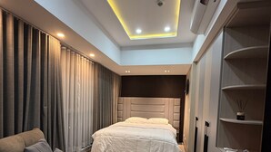 Un dormitorio moderno con cama, sofá, escritorio y armario.