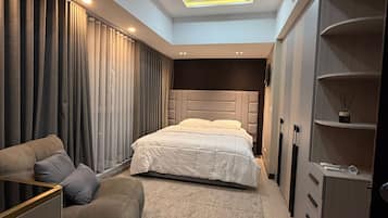 A modern bedroom with a bed, a sofa, a desk, and a wardrobe.