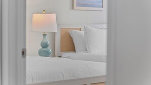 A bedroom with a bed, a nightstand with a lamp, and a framed picture on the wall.