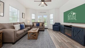 A modern living room with a sofa set, a coffee table, a TV, and a fireplace.