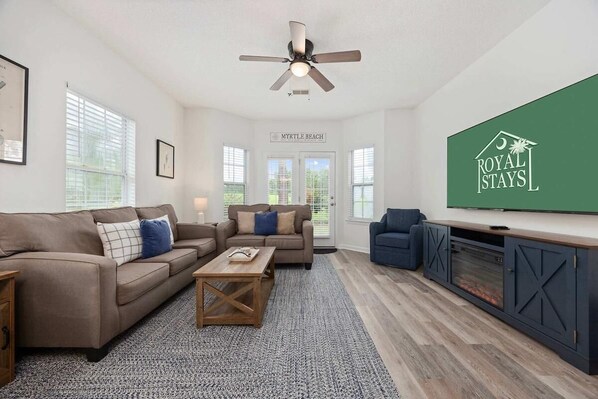 A modern living room with a sofa set, a coffee table, a TV, and a fireplace.