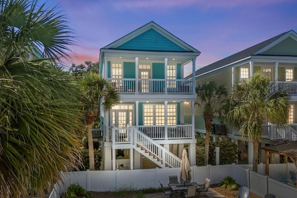 A two-story house with a balcony, a staircase, and a patio area with outdoor furniture.