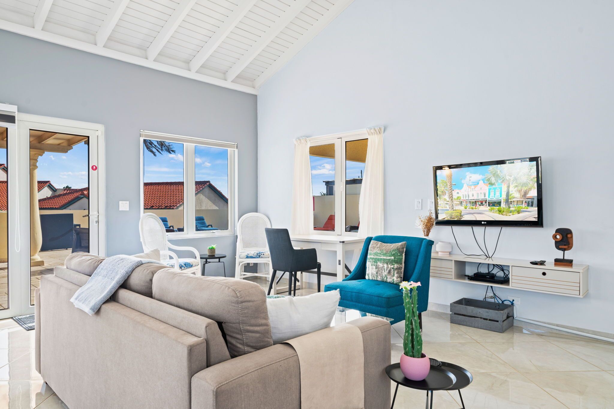 Un salon moderne avec un canapé, des fauteuils, un téléviseur et une vue sur l’extérieur.