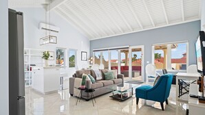 A spacious living area with a modern kitchen, a comfortable sofa, a glass coffee table, and a view of the outside. - Mesa Vista 36 Tierra del Sol (Noord)