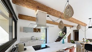 Una cocina moderna con una isla grande, vigas de madera e iluminación colgante.