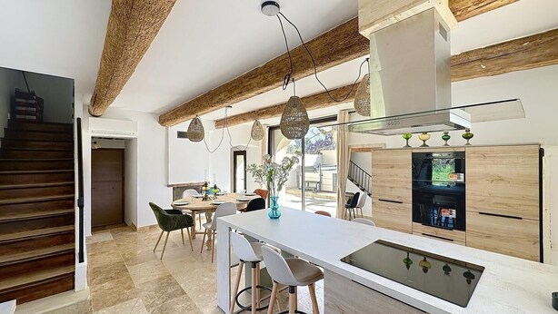 Una cocina moderna con una isla central, vigas de madera y un ventanal grande.
