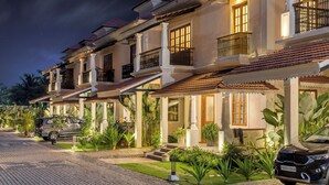 Une rangée de villas de style traditionnel, dotées de balcons, d’une allée pavée et d’une végétation luxuriante.
