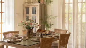 Une table à manger dressée avec des assiettes, des bols et un vase de fleurs.