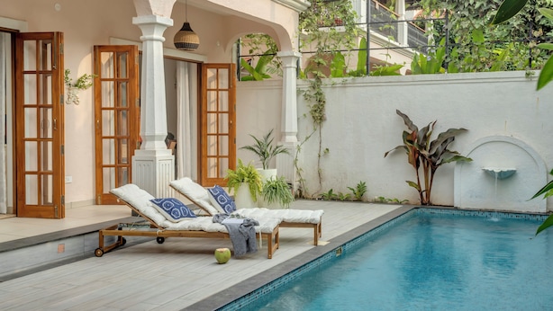 Un espace aménagé au bord de la piscine, avec des chaises longues, une petite table et une plante en pot.
