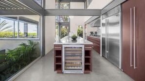 Cozinha moderna com ilha central, eletrodomésticos de aço inoxidável e grandes janelas.
