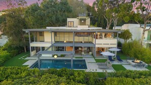 Uma casa moderna com dois andares, piscina, área de estar ao ar livre e um jardim bem cuidado.