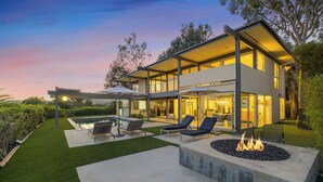 Uma casa moderna de dois andares com piscina, área de estar externa e lareira.