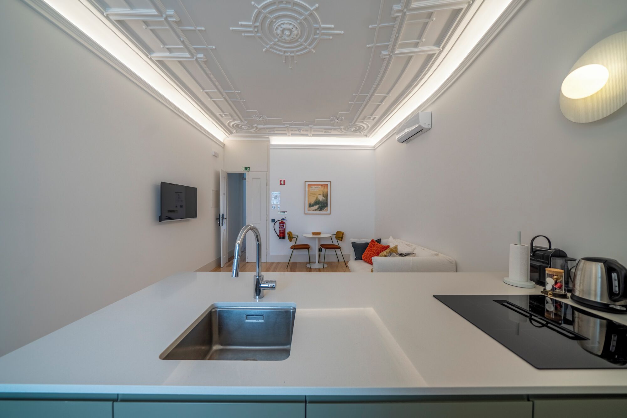 Een moderne keuken met een ingebouwde spoelbak, een eethoek met tafel en stoelen, en een bank.