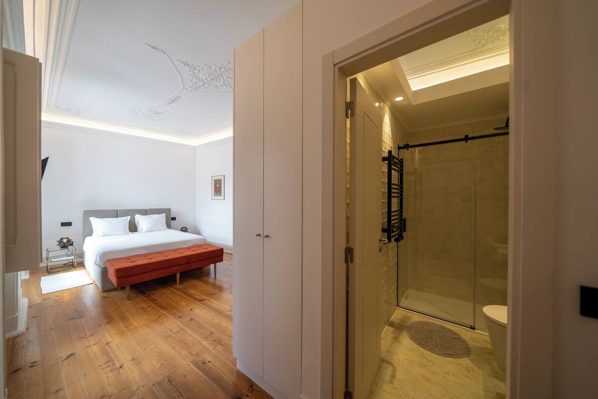 A bedroom with a bed, a bench, and a walk-in closet.