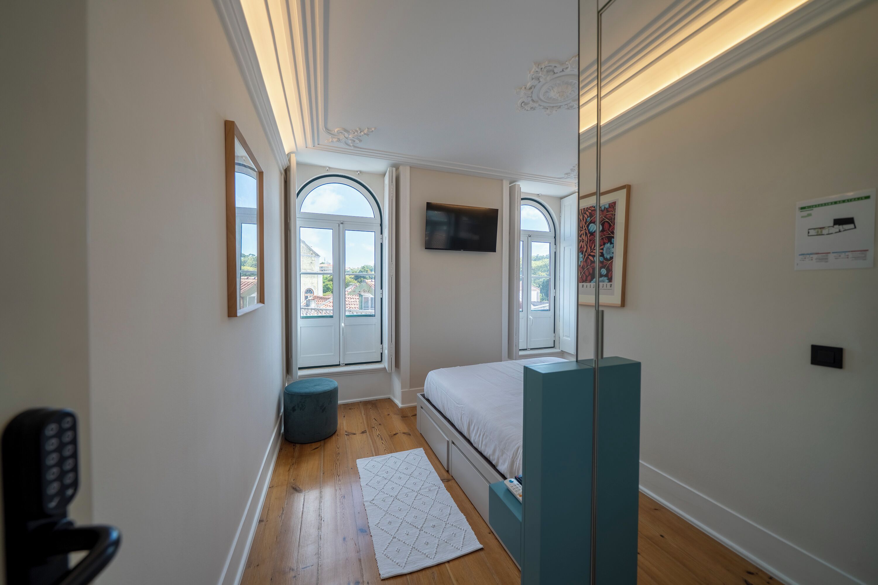 A bedroom with a bed, a TV, a window, and a door.
