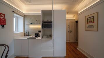 A compact kitchen with white cabinetry, a built-in microwave, and a sink.