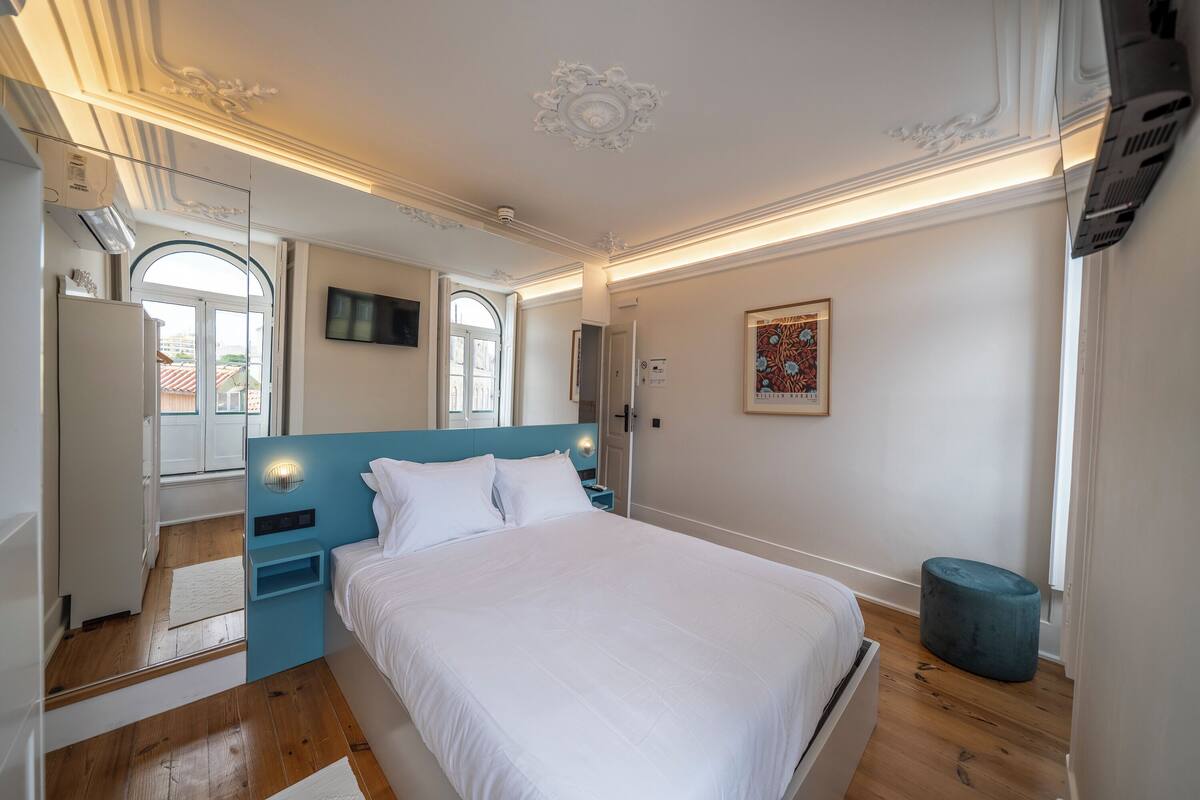 A bedroom with a bed, a TV, a window, and a door.