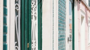 A building facade with ornate green window frames and a white wall. - Good Old Days (Caldas da Rainha)