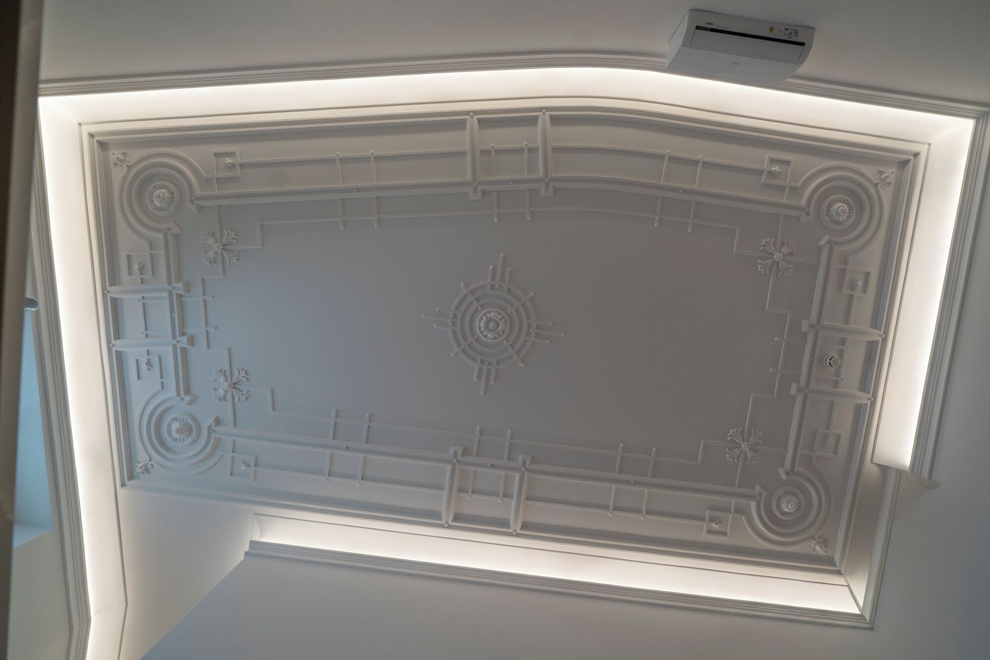 A ceiling with a central circular design and symmetrical patterns.