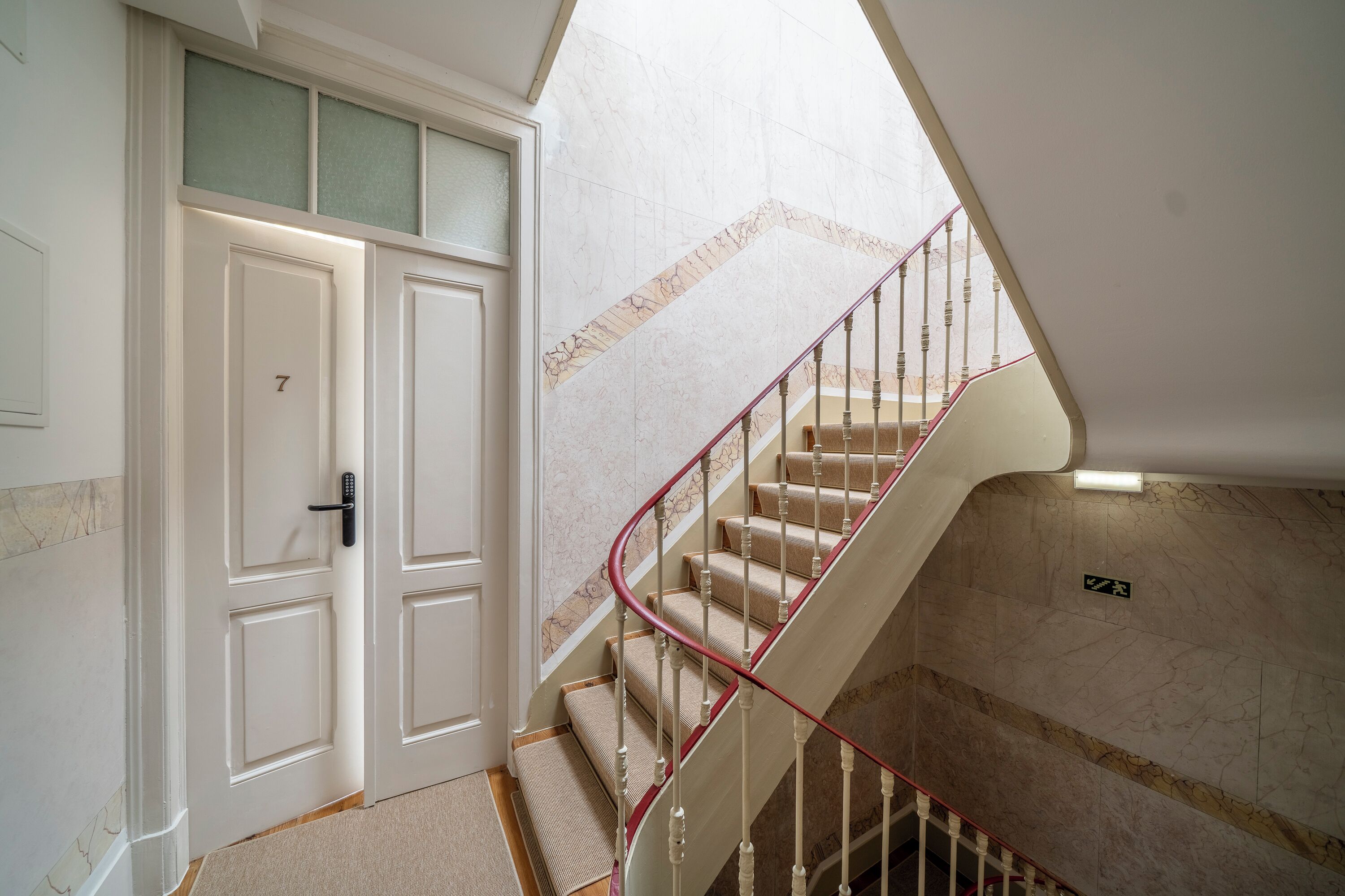 A staircase with a red handrail leading to a landing.