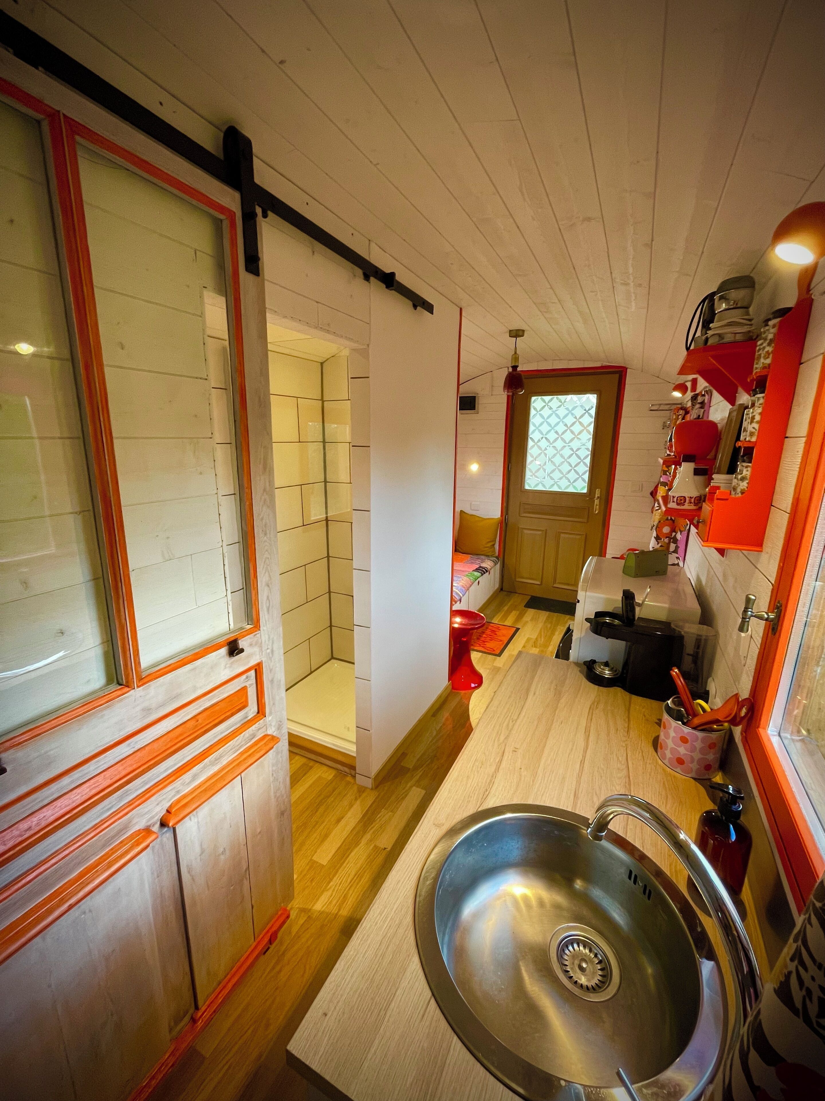 Een compacte keuken met een spoelbak, een raam met uitzicht en een deur naar een badkamer.