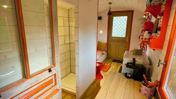 Een compacte keuken met een spoelbak, een raam met uitzicht en een deur naar een badkamer.