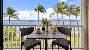A balcony with a table set for two, overlooking a beach with palm trees and the ocean. - Oceanfront Studio at Lahaina Shores #313 (Lahaina)