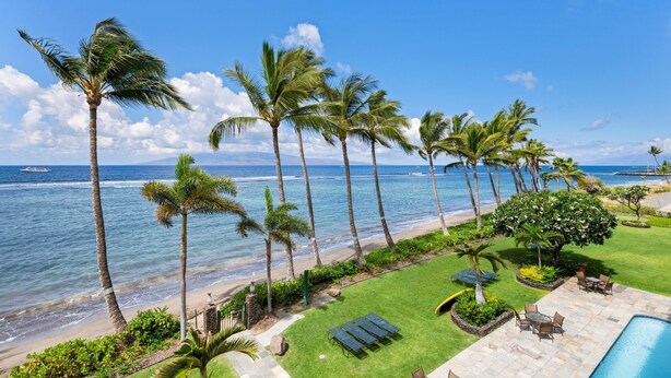 A beachfront property with a pool, lounge chairs, and palm trees. - Oceanfront Studio at Lahaina Shores #313 (Lahaina)