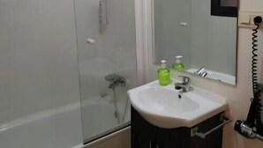 Une salle de bain avec une douche à parois de verre, un lavabo avec un miroir et des toilettes.