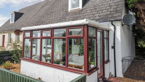 Una casa con un invernadero que cuenta con numerosas ventanas y fachada blanca.