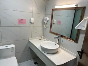 A hotel bathroom with a white sink, a mirror, and a hairdryer on the wall. - ANHUI HÔTEL  (Lomé)