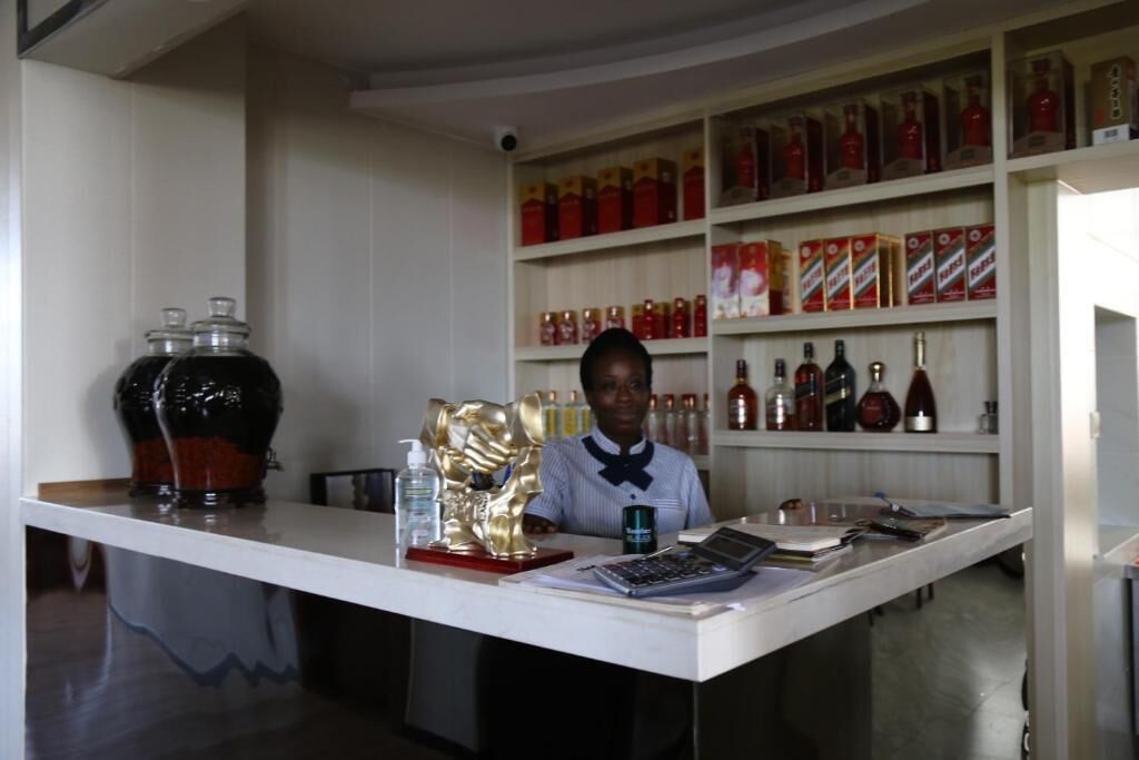 A bar area with a counter, shelves stocked with bottles, and a large decorative vase.