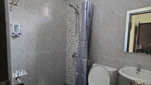 A bathroom with a shower, toilet, and sink. - Shini Guest House (Malang)