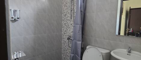 A bathroom with a shower, toilet, and sink.