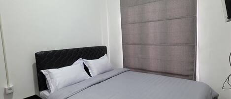 A bedroom with a bed, a nightstand, a wall-mounted air conditioner, and a wall-mounted television.