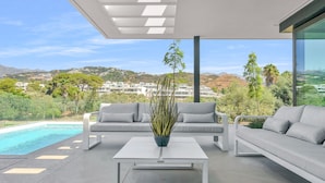 A modern outdoor living area with a pool, two sofas, and a coffee table. - Villa Soul (Marbella)