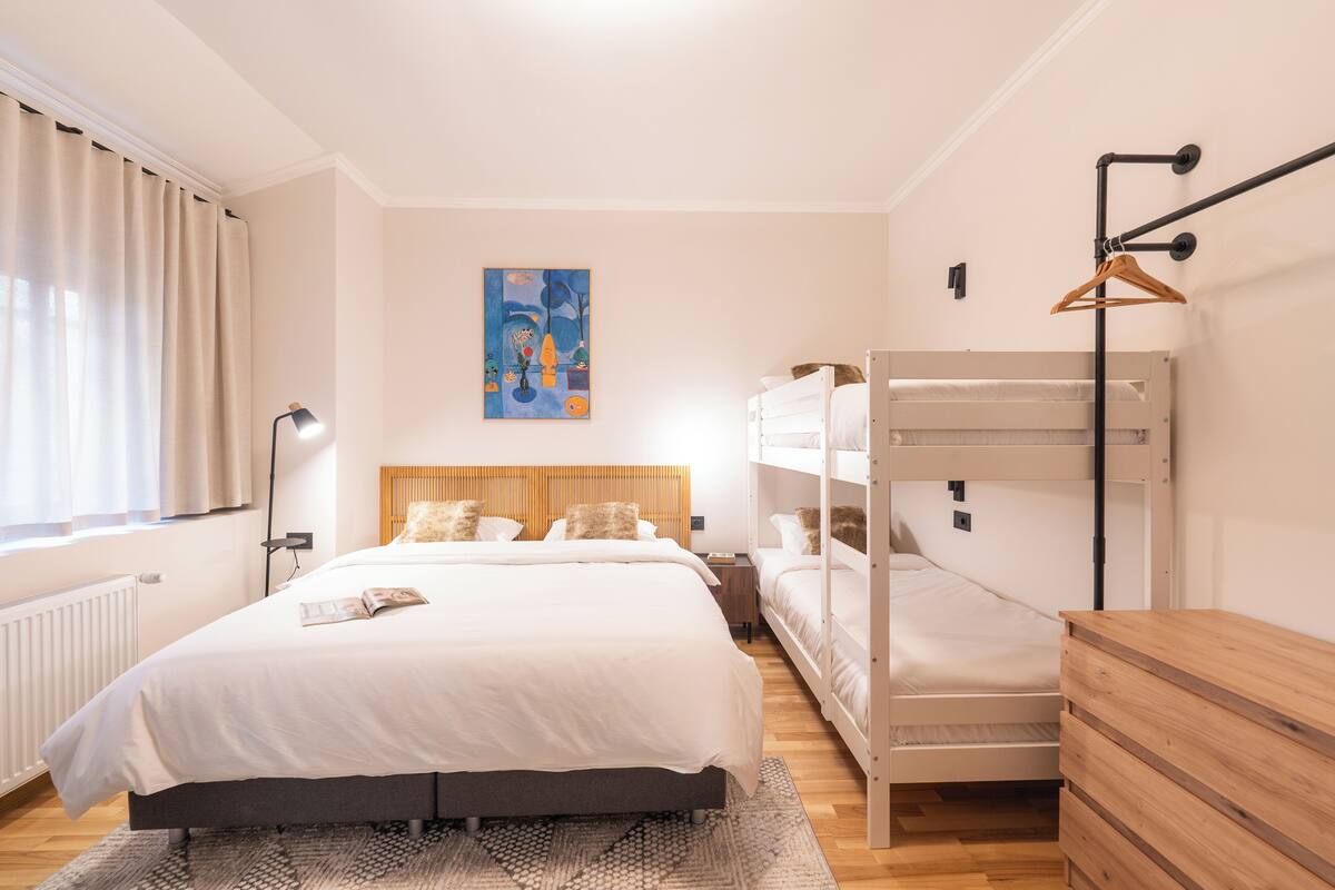 Une chambre à coucher avec un lit superposé, une table de chevet, une lampe et un tableau accroché au mur.