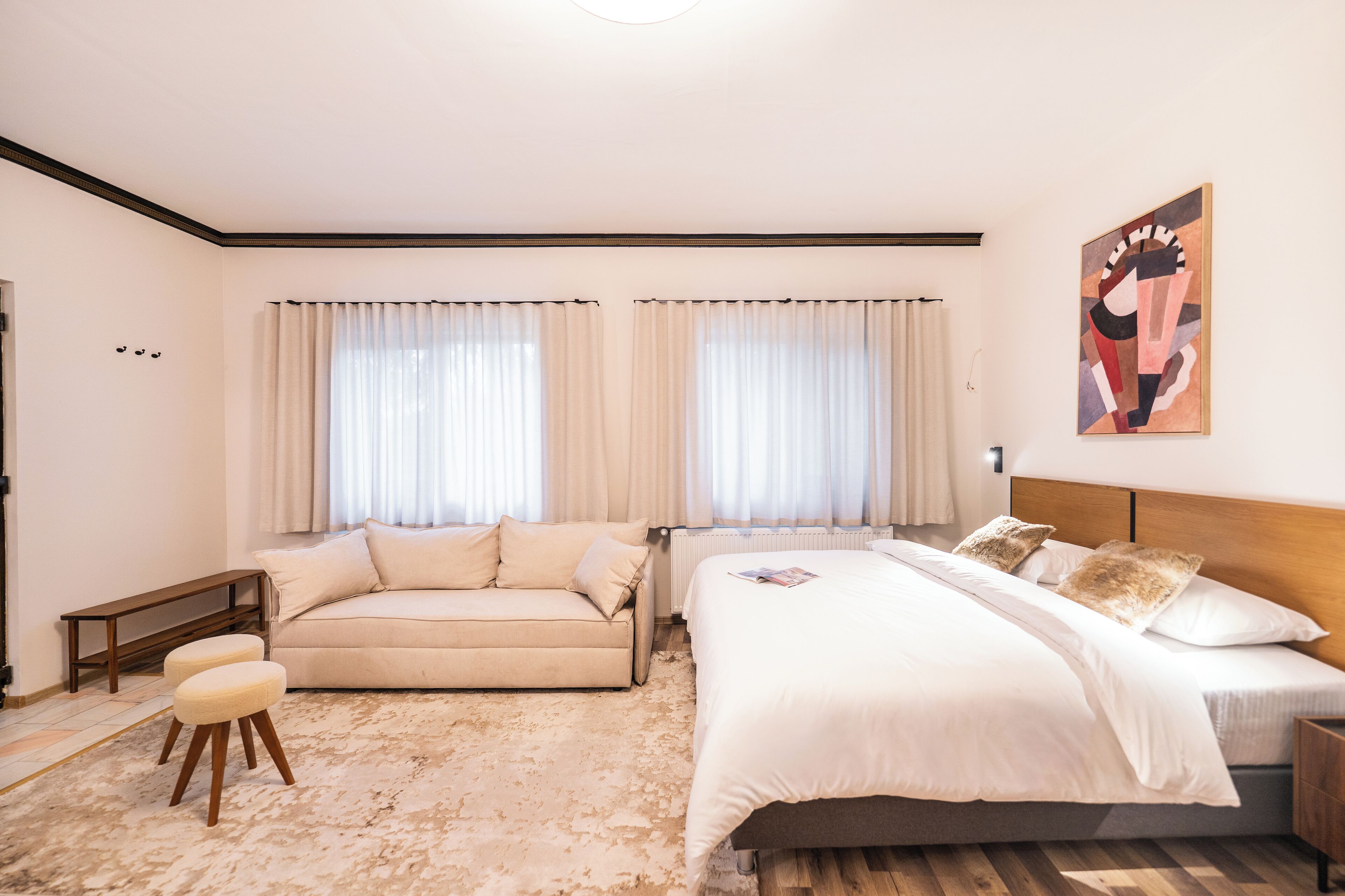 Um quarto com uma cama, um sofá, um banco e um pequeno banquinho.