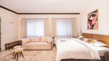 Um quarto com uma cama, um sofá, um banco e um pequeno banquinho.