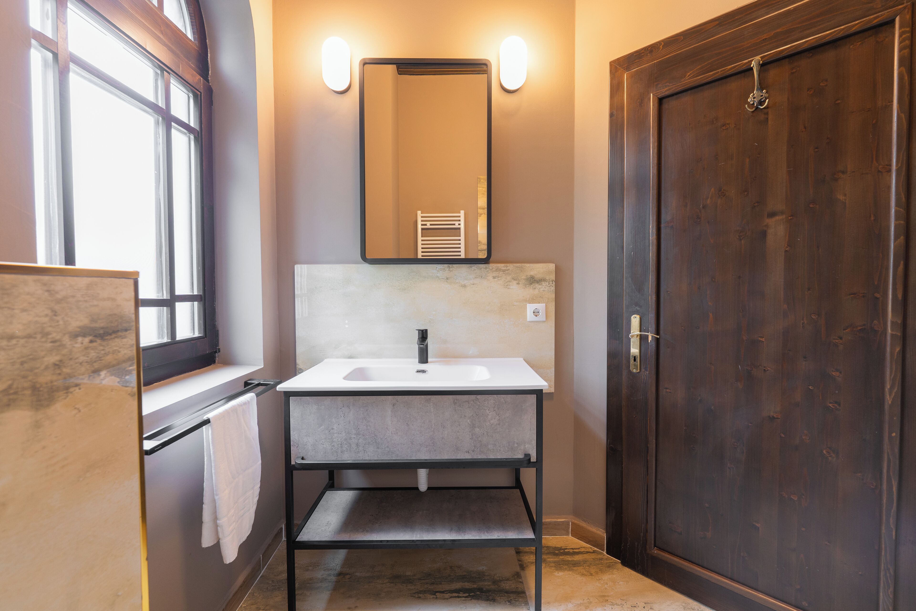 A bathroom with a white sink, a mirror, and a wooden door.