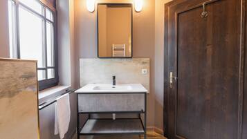 A bathroom with a white sink, a mirror, and a wooden door.