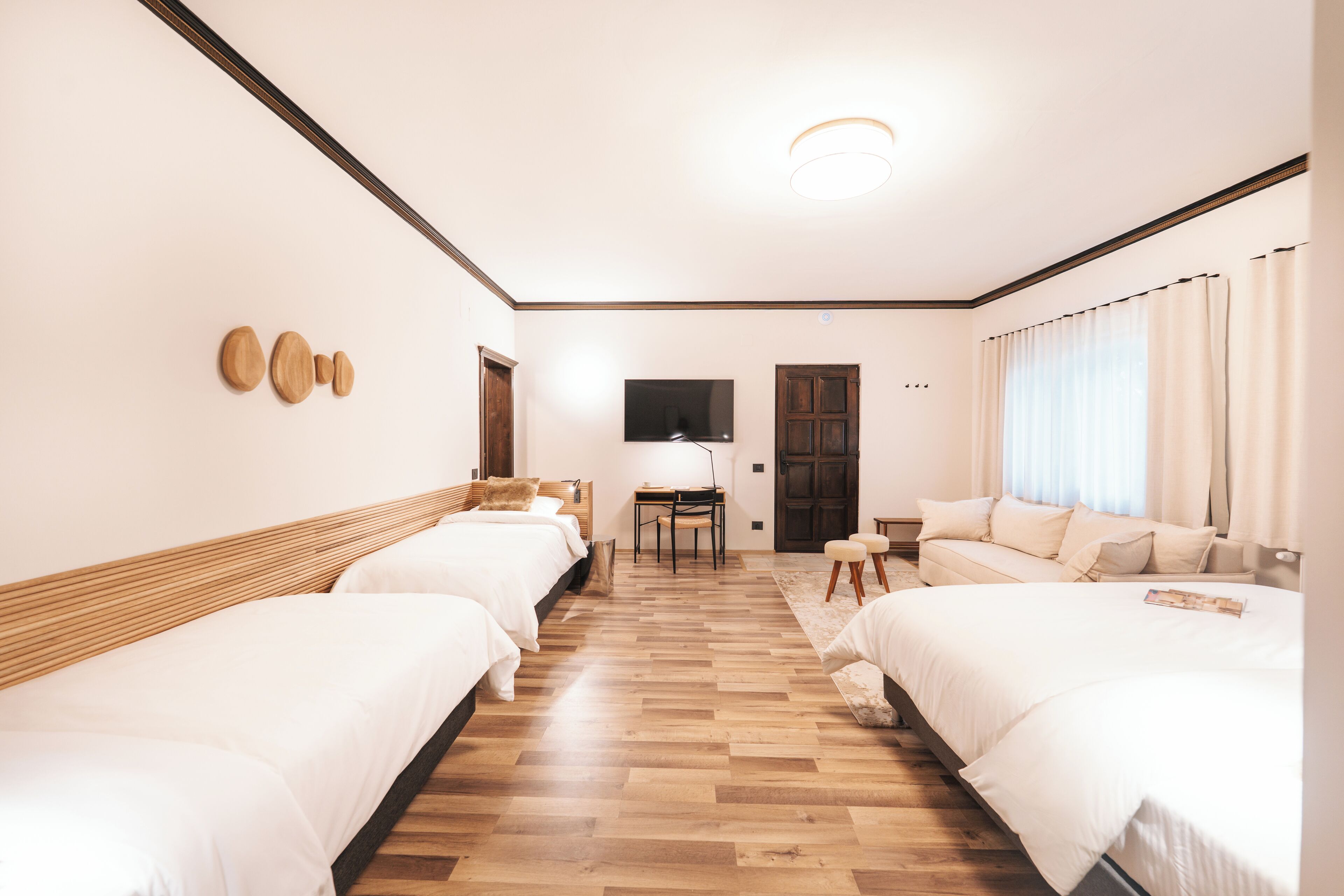 Habitación de hotel con dos camas, un escritorio, un televisor y una ventana con cortinas.