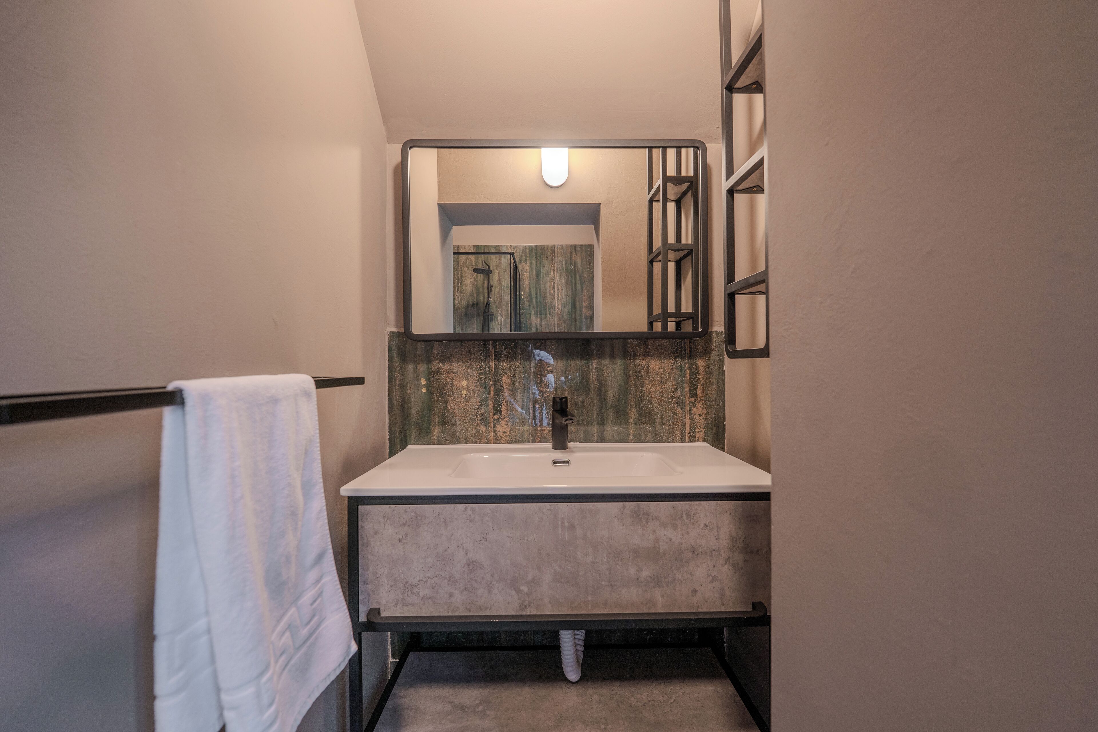 A bathroom with a white sink, a towel hanging on a rack, and a mirror above the sink.