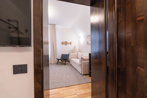Una sala de estar moderna con un sofá, una silla, un tapete y un televisor montado en la pared.
