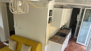 Un ambiente compatto con divano, angolo cottura e porte scorrevoli in vetro.