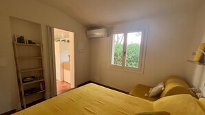 Una camera da letto con un letto, una finestra, un condizionatore d'aria, una libreria e una porta che dà su un'altra stanza.